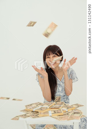A woman rejoices as 10,000 yen bills fall from a stack of bills 131142490