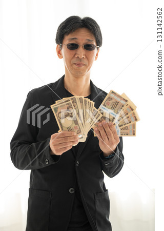 一名身穿黑衣的男子手持一疊新版 1 萬日圓鈔票 131142562