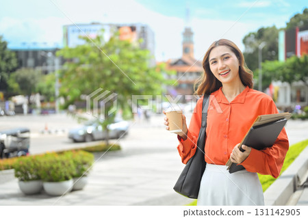 Confident businesswoman enjoying coffee break while walking in urban street Confident businesswoman enjoying coffee break while walking in urban street 131142905