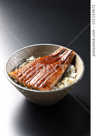Eel bowl photographed alone against a black background 131143672