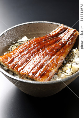 Eel bowl photographed alone against a black background 131143678