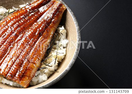 Eel bowl photographed alone against a black background 131143709