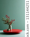 Round red podium with green background showcasing festive arrangement of red berries and greenery 131144251
