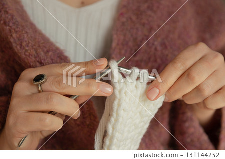 Knitting needles with threads close-up. Knitter's hands close-up. 131144252