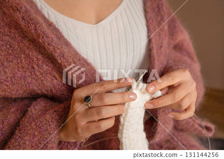 Hands knitting with white yarn and needles 131144256