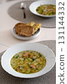 Homemade salmon soup with potatoes and herbs, served in white bowl on dining table 131144332