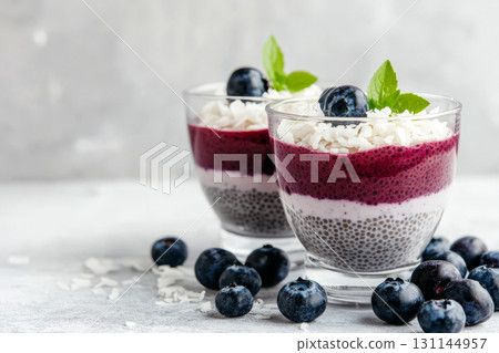 Two parfaits feature layers of chia pudding topped with blueberries and coconut flakes, creating a healthy dessert perfect for any occasion Two parfaits feature layers of chia pudding topped with blueberries and coconut flakes, creating a healthy dessert perfect for any occasion 131144957