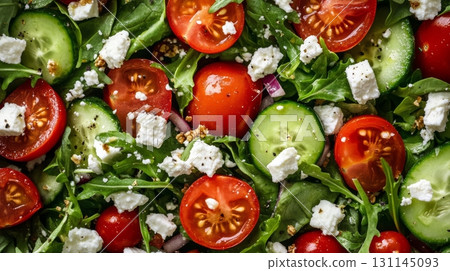Colorful salad composed of mixed greens, cherry tomatoes, cucumbers, and feta cheese, garnished with crunchy granola for added flavor 131145093