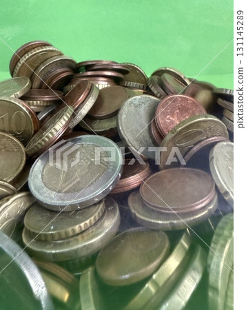 Close-up of Euro coins in container. Glass piggy bank for money. Saving money to buy necessary things. 131145289
