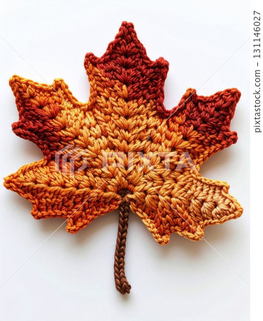 Handmade Crochet Maple Leaf with Gradient of Orange Yellow and Brown Colors on White Background Handmade Crochet Maple Leaf with Gradient of Orange Yellow and Brown Colors on White Background 131146027