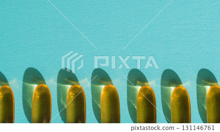 Softgel capsules with long shadows on teal paper, close up Softgel capsules with long shadows on teal paper, close up 131146761