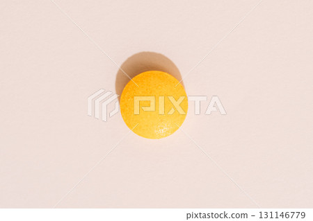 Single orange tablet on beige background, top view with hard shadow Single orange tablet on beige background, top view with hard shadow 131146779