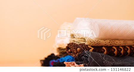 Rolled lace fabrics on peach surface, side view 131146822
