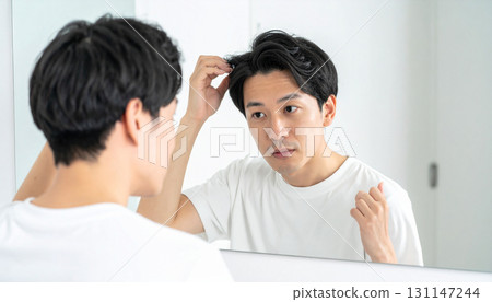 A young man concerned about his thinning hair (AI-generated image) A young man concerned about his thinning hair (AI-generated image) 131147244