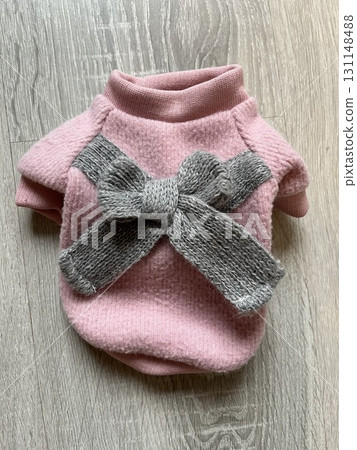 Pink dog sweater with grey knitted bow on wooden surface 131148488