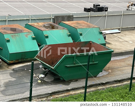 Green industrial dumpsters collecting commercial waste at storage site 131148510
