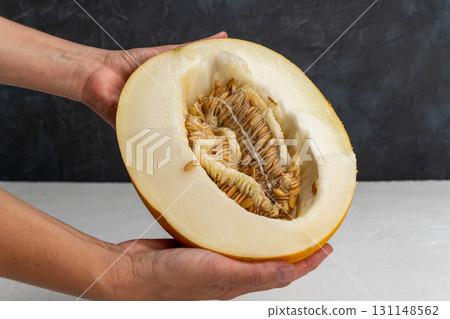 Hands holding half ripe fresh melon with seeds 131148562