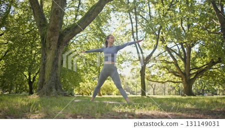 young beautiful white girl doing yoga in park among trees in clearing on summer day young beautiful white girl doing yoga in park among trees in clearing on summer day 131149031