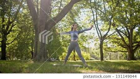 young beautiful white girl doing yoga in park among trees in clearing on summer day young beautiful white girl doing yoga in park among trees in clearing on summer day 131149044