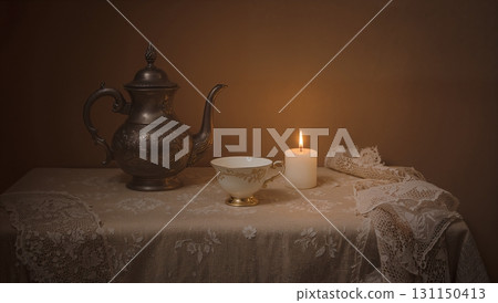 A tea kettle and a candle are on a table 131150413