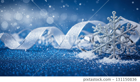 A sparkling snowflake and silver ribbon on a glittery blue background, celebrating the magic of winter and Christmas. 131150836