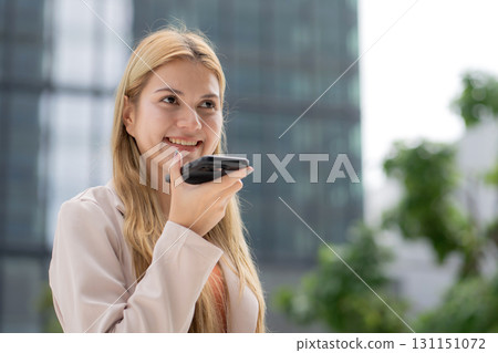 Young caucasian businesswoman using voice message on smartphone with chatbot or AI. 131151072