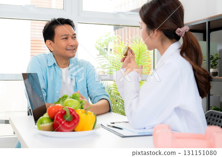 Asian nutritionist holding fresh fruits vegetables during consultation with patient in clinic. Asian nutritionist holding fresh fruits vegetables during consultation with patient in clinic. 131151080
