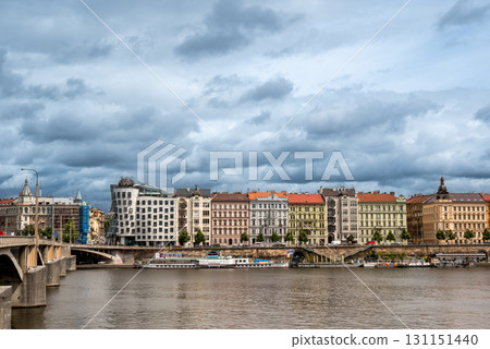 Prague, Czech Republic, August 7, 2023. Panoramic shot of the Dancing House along the Vltava River: futuristic shapes and modern materials alongside colorful historic buildings. Travel destinations. 131151440