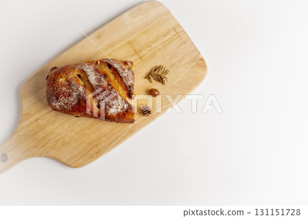 A delicious, warm, brown loaf of bread sits on a cutting board against a white background, decorated with autumnal objects. Studio photo. Concept photo. Top view. 131151728