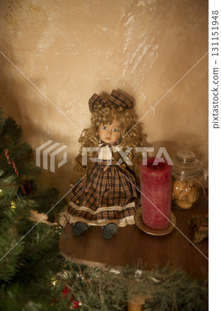 Cute vintage doll sits on a shelf near a Christmas tree Cute vintage doll sits on a shelf near a Christmas tree 131151948