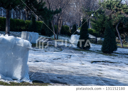 winter in the city park, grass is visible under the snow 131152180