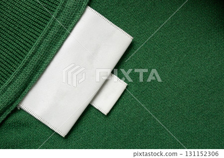 Blank white laundry care clothes label on green shirt fabric texture background Blank white laundry care clothes label on green shirt fabric texture background 131152306