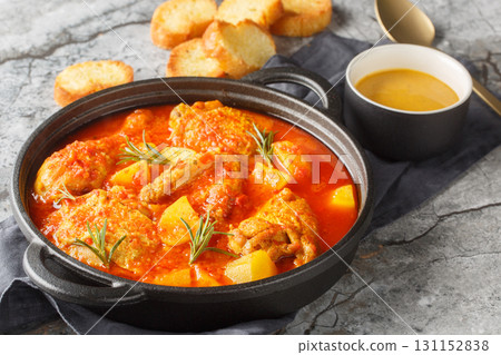 Chicken Bouillabaisse is comforting stew featuring tender chicken pieces simmered in a saffron-tomato broth infused with garlic, fennel, and white wine closeup in the saucepan. Horizontal 131152838