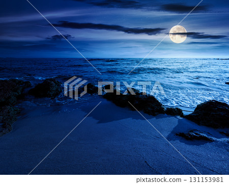beach with sand at night. summer vacation at the seaside. beautiful seascape with calm waves in full moon light. landscape at the sea under sky with fluffy clouds 131153981
