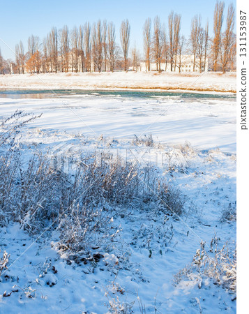 uzhhorod, ukraine - 3 jan, 2009: uzh river in winter. trees on the riverbank. beautiful urban scenery. cityscape on a frosty sunny day. old town outdoor adventure uzhhorod, ukraine - 3 jan, 2009: uzh river in winter. trees on the riverbank. beautiful urban scenery. cityscape on a frosty sunny day. old town outdoor adventure 131153987