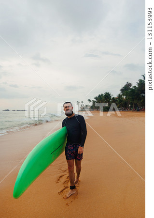 Surfer holding surf board on the beach at sunset. Happy man guy having fun doing extreme sport 131153993