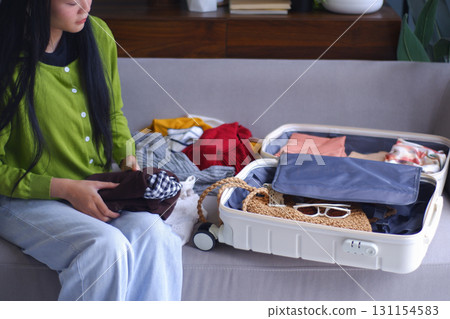 Young Asian women folding clothes, packing luggage for holiday trip. 131154583
