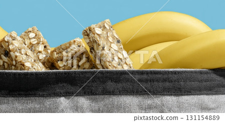Healthy snacks like granola bars and bananas spill from a gym bag in a sunny setting 131154889