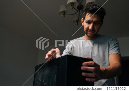 Low-angle view of technician male wiping computer case, removing dust and grime for maintaining electronic device cleanliness and functionality. Concept of cleaning PC for optimal performance. 131155022