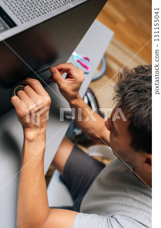 Vertical top view of technician applying black electrical tape while performing computer case repair, showing diy troubleshooting technique at workshop. Concept of desktop PC maintenance and service. 131155041