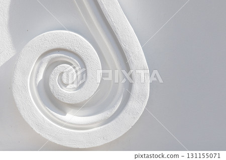 A close-up of a carved white spiral molding, showcasing smooth curve texture A close-up of a carved white spiral molding, showcasing smooth curve texture 131155071