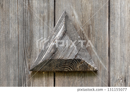 A weathered wooden triangle sits against gray planks, vintage door decor 131155077