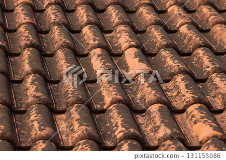 Close-up view of old terracotta roof tiles showing patina and rust marks 131155086