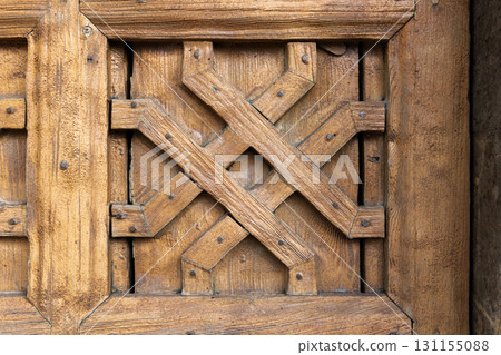 Weathered wooden door panel with decorative crossed planks, close up photo 131155088