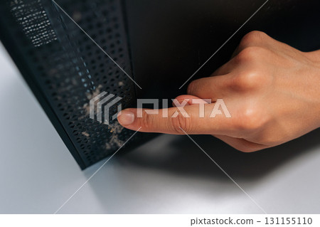 Close-up of technician pointing at thick layer of dust on computer air vents, emphasizing importance of regular cleaning and maintenance to avoid overheating and hardware failure. Close-up of technician pointing at thick layer of dust on computer air vents, emphasizing importance of regular cleaning and maintenance to avoid overheating and hardware failure. 131155110