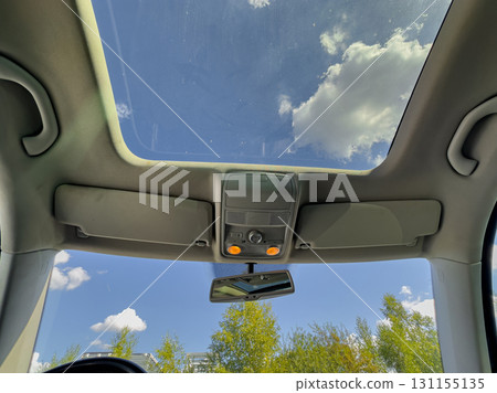 Open sunroof allows sunlight to stream in while driving through a bright, blue sky on a sunny day filled with fluffy white clouds Open sunroof allows sunlight to stream in while driving through a bright, blue sky on a sunny day filled with fluffy white clouds 131155135