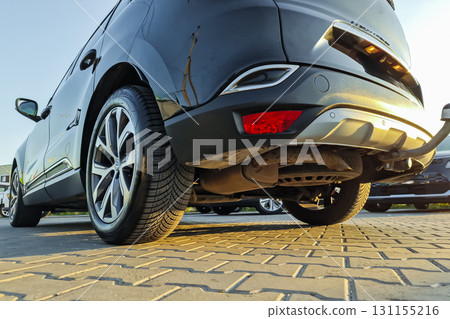 Under the sunlight, a sleek black vehicle parked with precision on a patterned surface during the calm evening hours at a bustling car lot Under the sunlight, a sleek black vehicle parked with precision on a patterned surface during the calm evening hours at a bustling car lot 131155216