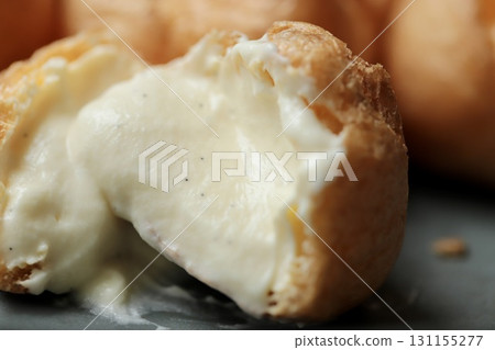 A cross section of a petit cream puff with a soft skin and plenty of cream 131155277