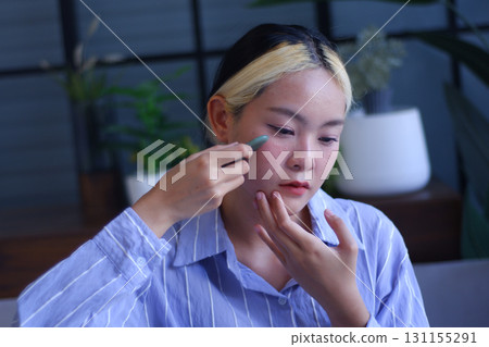 Young Asian women massage her face with Gua-Sha therapy to promote blood circulation and lymphatic drainage to relieve tension, pain and inflammation, and improve health beauty. Young Asian women massage her face with Gua-Sha therapy to promote blood circulation and lymphatic drainage to relieve tension, pain and inflammation, and improve health beauty. 131155291