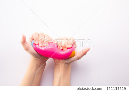 Hand squeeze pink stress ball on white background. Positive thinking concept. Copy space Hand squeeze pink stress ball on white background. Positive thinking concept. Copy space 131155329